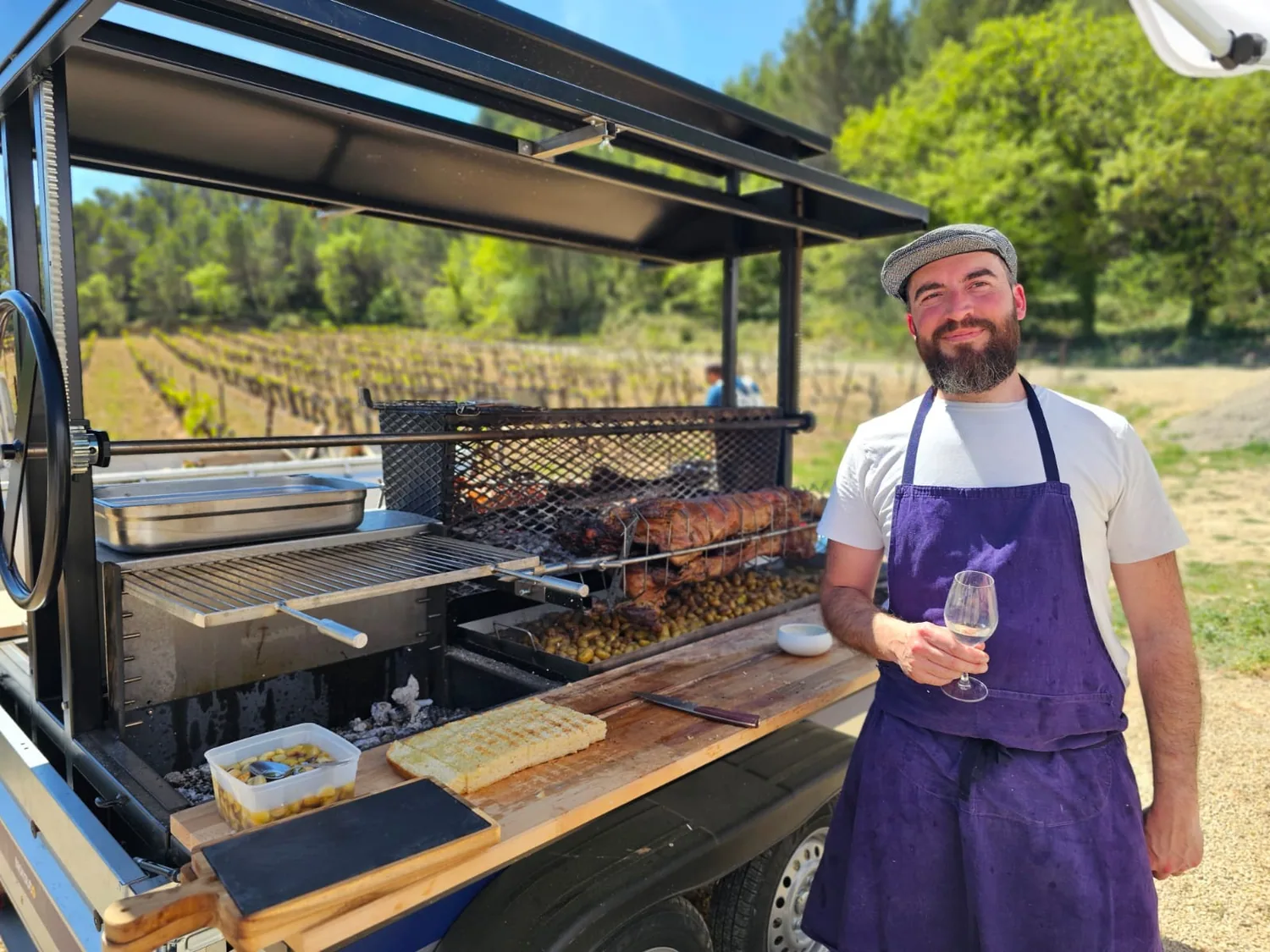 Le cuisinier du Gramboisien devant son tournebroche au milieu des vignes