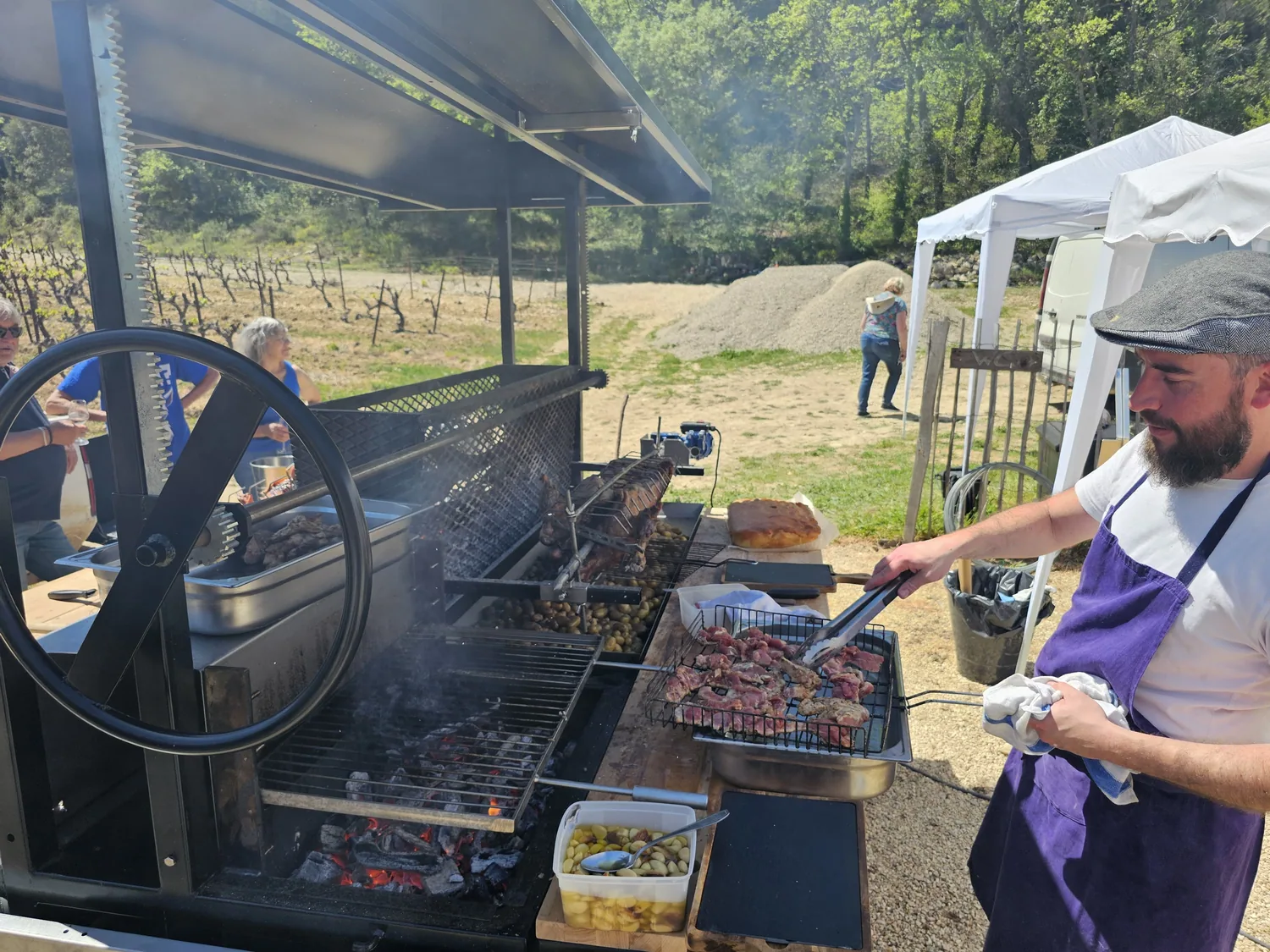 Le cuisinier saisit de la viande au-dessus des braises.